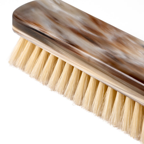 Side view of the layered natural horn clothing brush, highlighting the unique horn pattern.