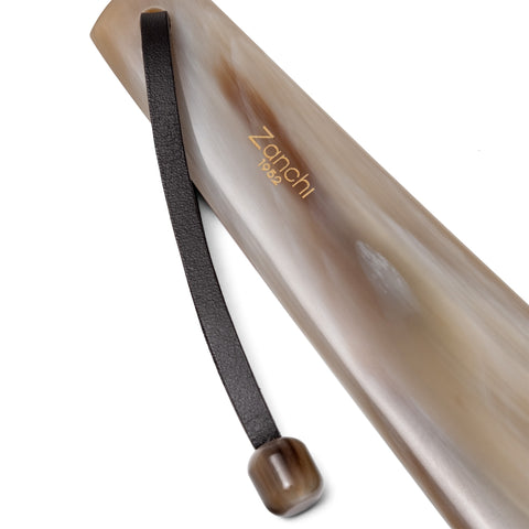 Close-up of luxury handcrafted shoehorn with leather lace and natural horn stopper – Italian craftsmanship