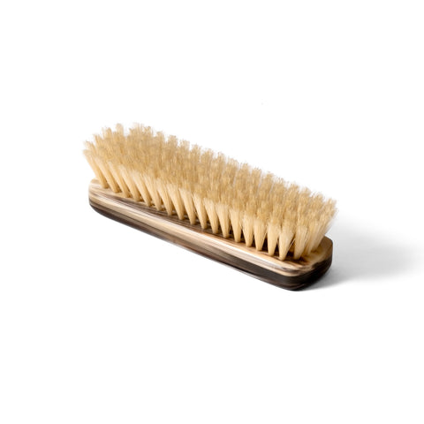 Natural horn clothing brush being used on a wool garment, demonstrating lint removal.