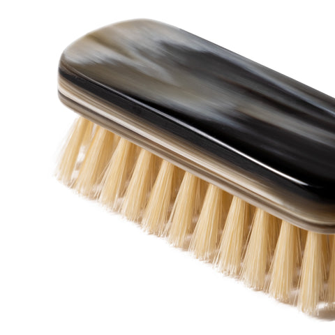 Side view of the layered natural horn shoe brush, showing the distinctive horn grain and shape.